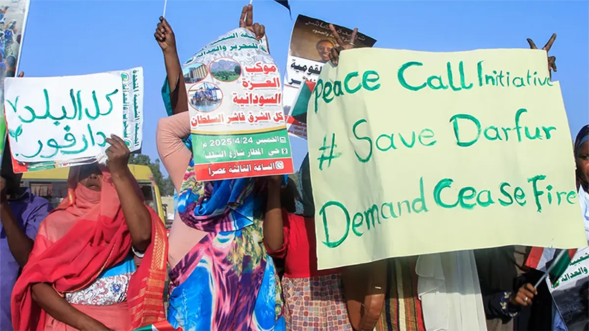 Protesters holding handwritten signs demanding a ceasefire and protection for Darfur, Sudan, including a prominent yellow sign reading Peace Call Initiative Save Darfur Demand Cease Fire