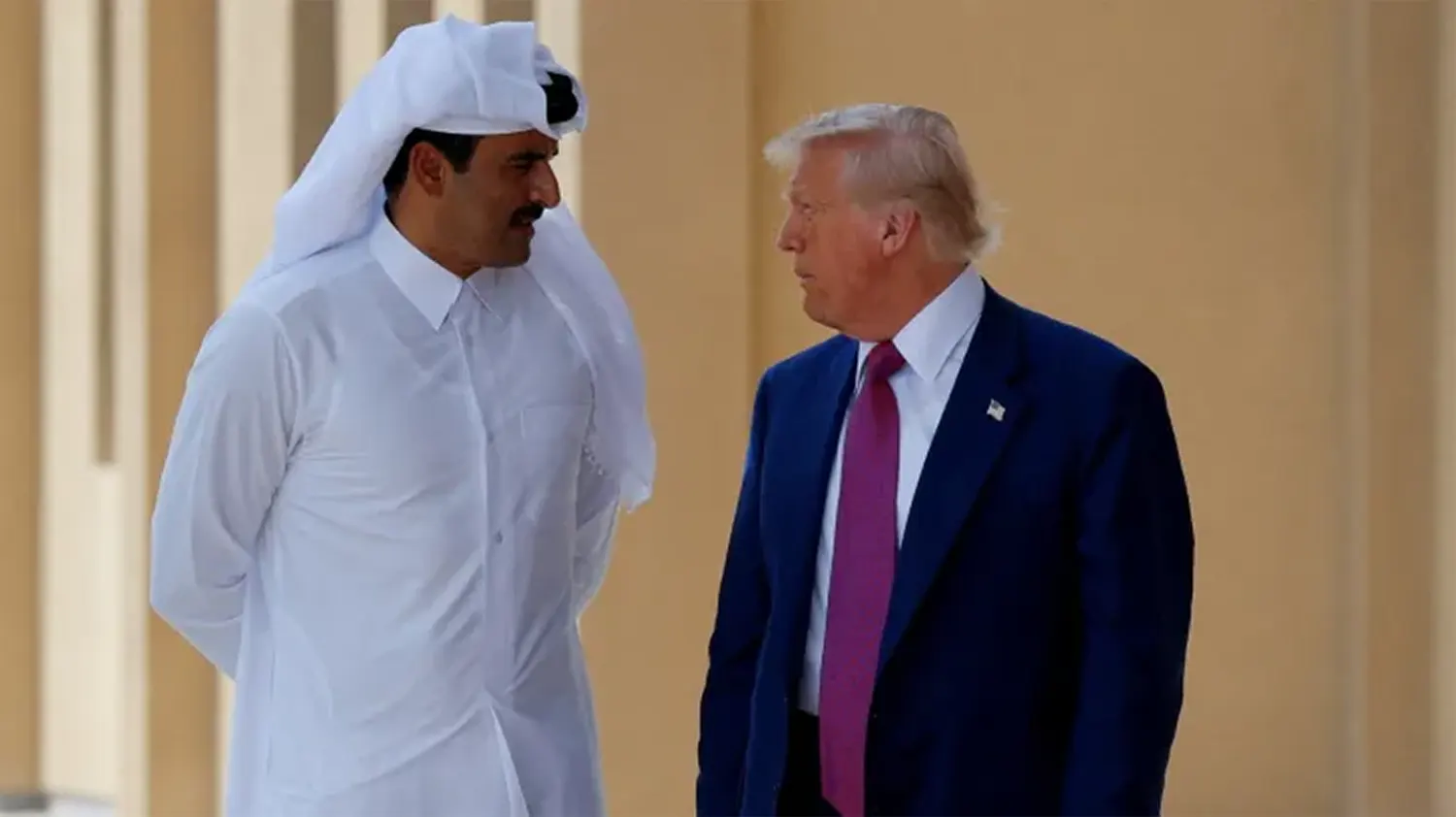 President Donald Trump in a blue suit and red tie talking closely with the Amir of Qatar, Sheikh Tamim bin Hamad Al Thani, who is wearing a traditional white thobe and ghutra, during a high-stakes diplomatic meeting in September 2025.