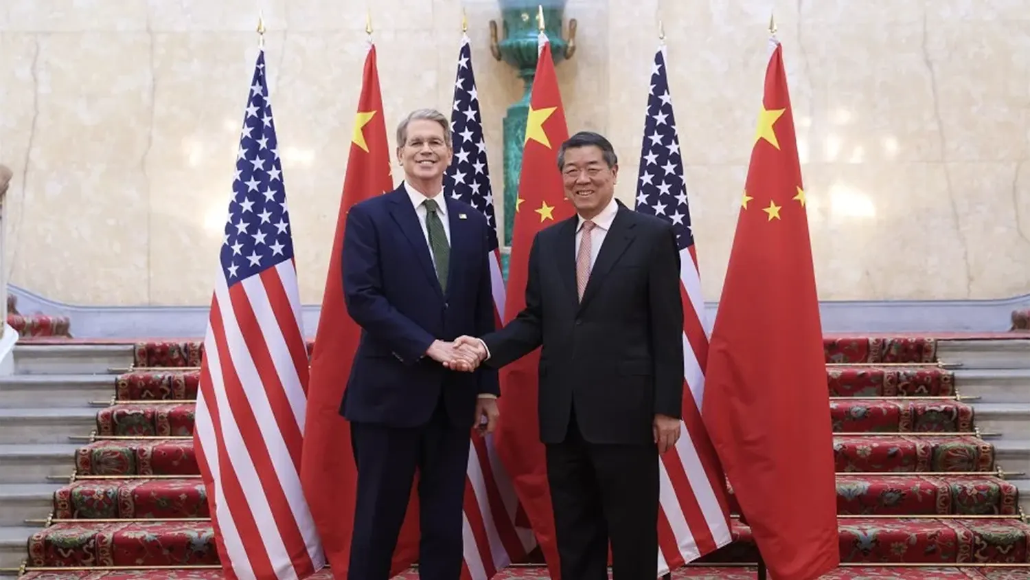 U.S. and Chinese officials shaking hands in front of alternating American and Chinese flags during the September 2025 trade summit in Madrid.