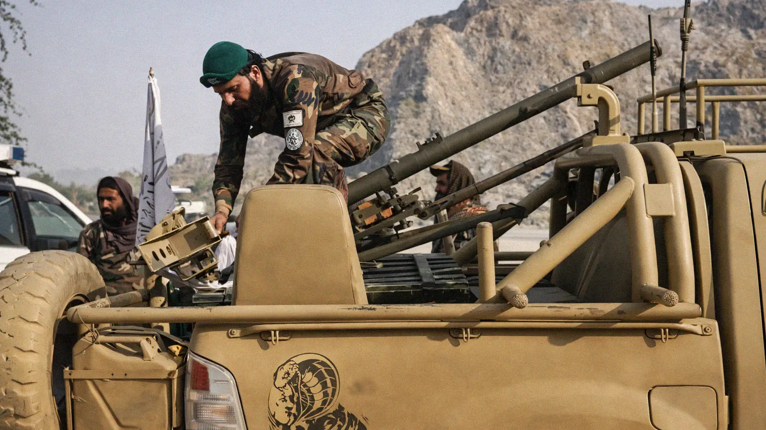 Taliban fighters preparing a mounted heavy weapon on a pickup truck in mountainous terrain during the Afghanistan–Pakistan border conflict