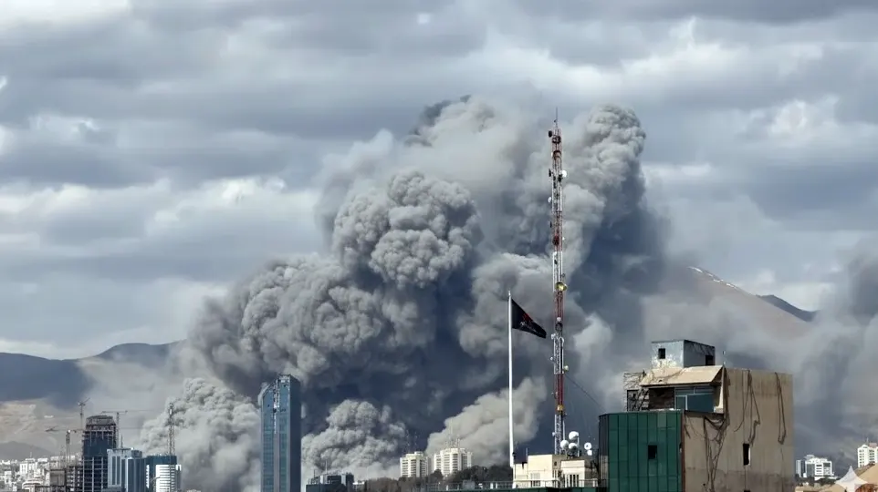 Large plumes of grey smoke rising from a Tehran city skyline after an Israeli airstrike during the 2026 conflict