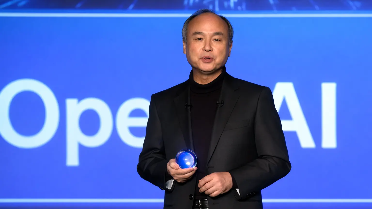 Masayoshi Son speaking at an OpenAI event, holding a glowing orb during a SoftBank AI investment presentation