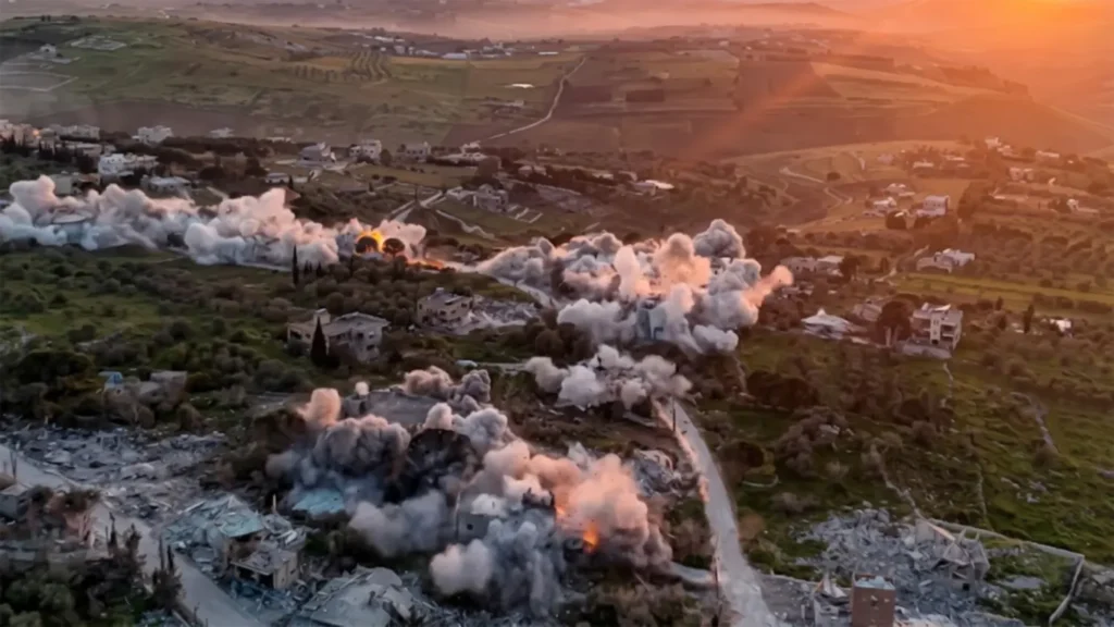 Aerial DSLR-quality view of systematic building demolitions and smoke plumes in a southern Lebanese village within the Tyre district during the April 2026 conflict escalation.