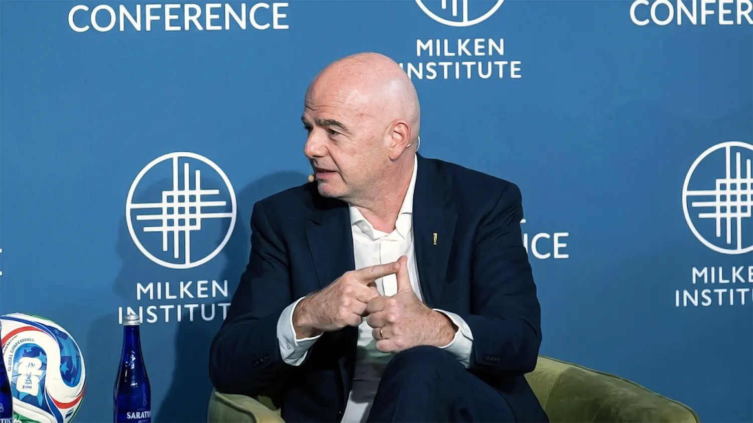 A professional high-resolution portrait of FIFA President Gianni Infantino speaking at a Milken Institute conference, featuring a sharp depth-of-field effect and detailed suit textures