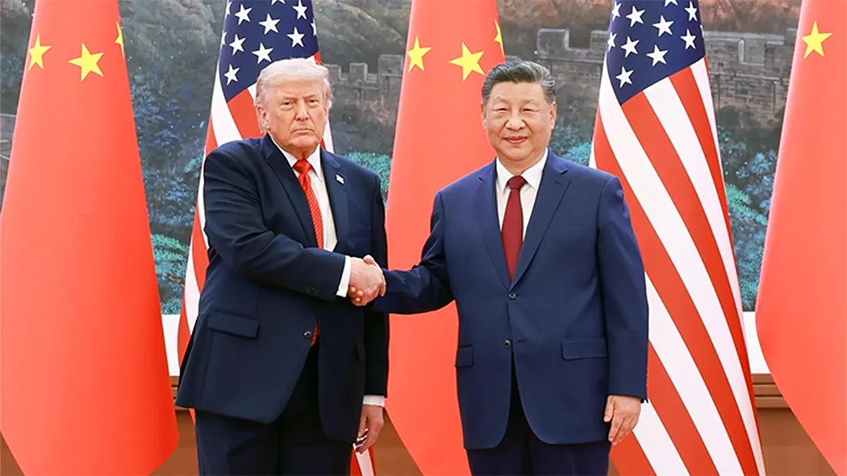 President Donald Trump and Chinese President Xi Jinping shaking hands in front of American and Chinese flags at the 2026 Beijing Summit