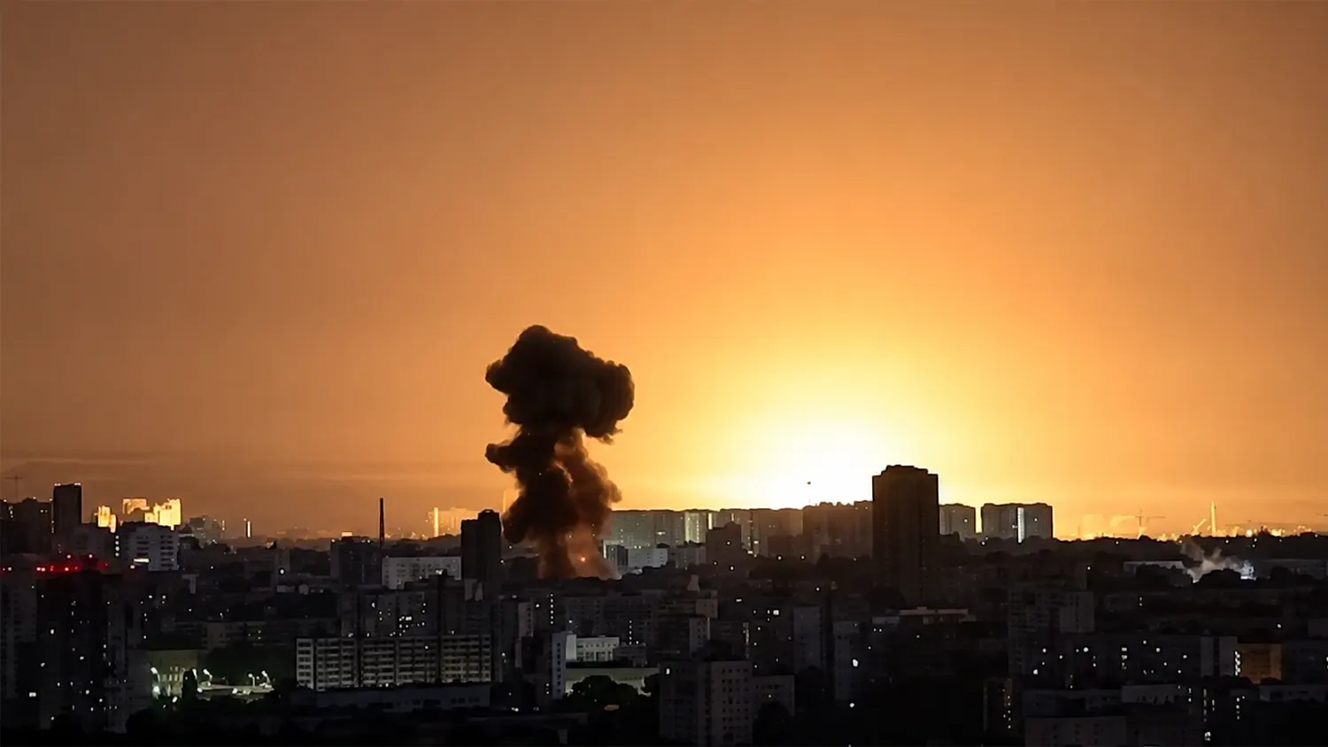 Large mushroom cloud from a missile strike explosion rising over a city skyline at dusk