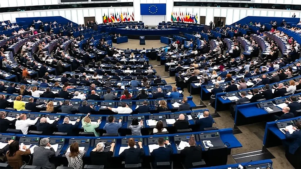 A wide high-resolution view of the European Parliament hemicycle in Brussels during an active plenary session with MEPs seated at desks.