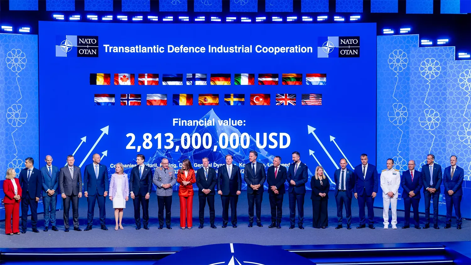 Official NATO photo of defense leaders on stage at the Ankara Summit in front of a blue screen displaying Transatlantic Defence Industrial Cooperation and a financial value of 2,813,000,000 USD.