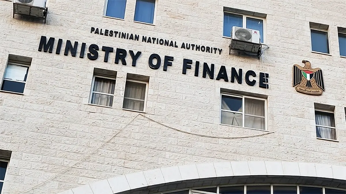 Exterior view of the Palestinian National Authority Ministry of Finance building, showing the official English signage and national emblem on a stone facade.