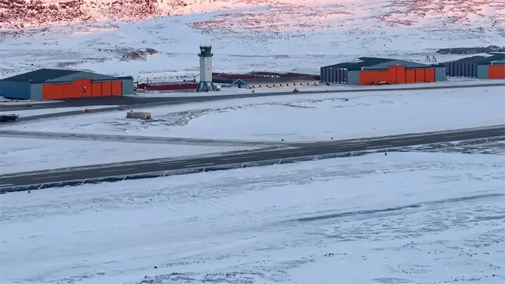 Aerial view of Pituffik Space Base runway and control tower in snow-covered Greenland landscape
